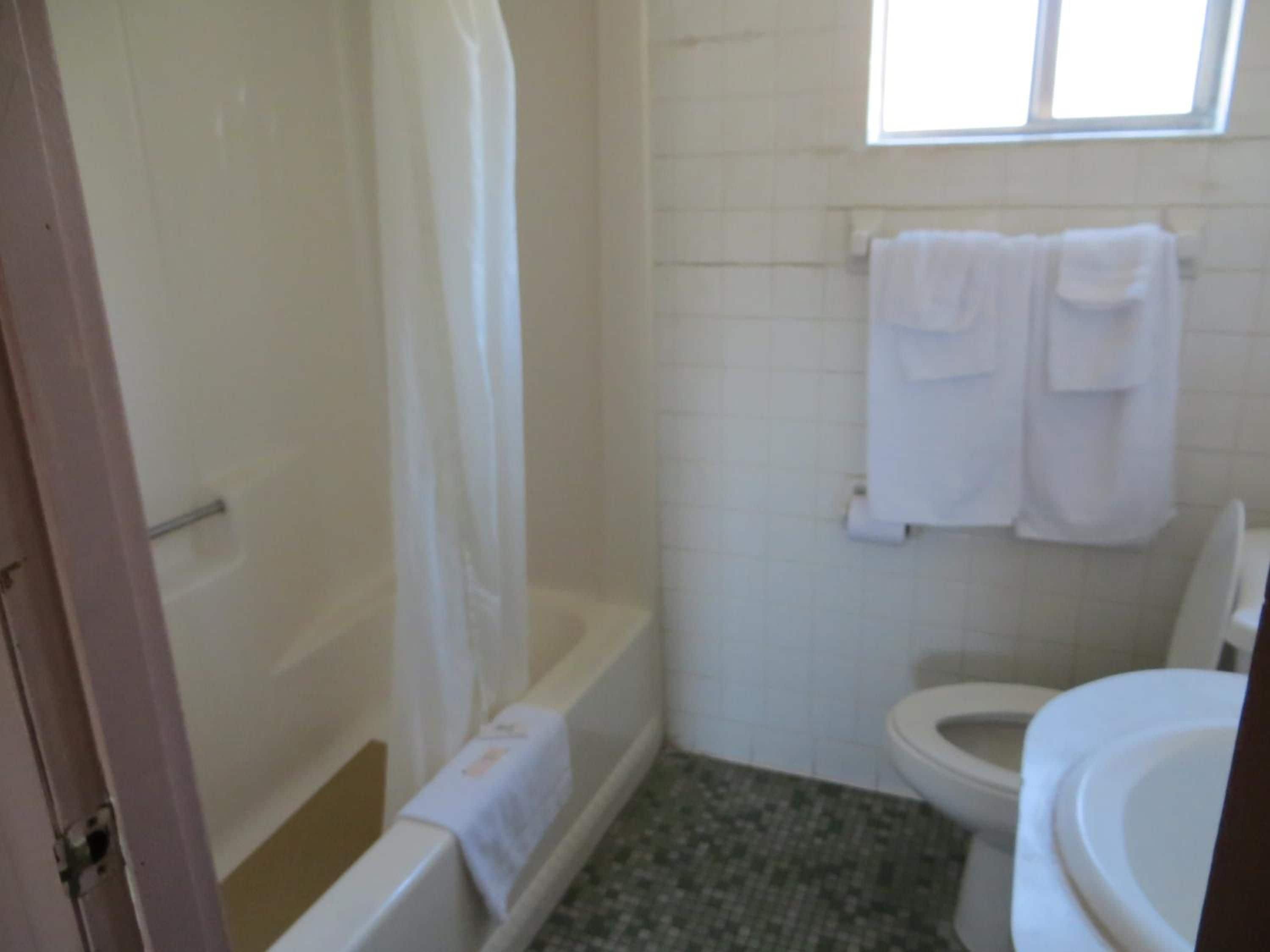 A bathroom with a bathtub, toilet, and a towel rack with towels.