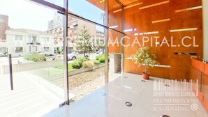 A modern building with large glass windows, a wooden interior, and a view of the street outside. - Apartamentos Premium Capital Casino Viña Del Mar (Vina del Mar)