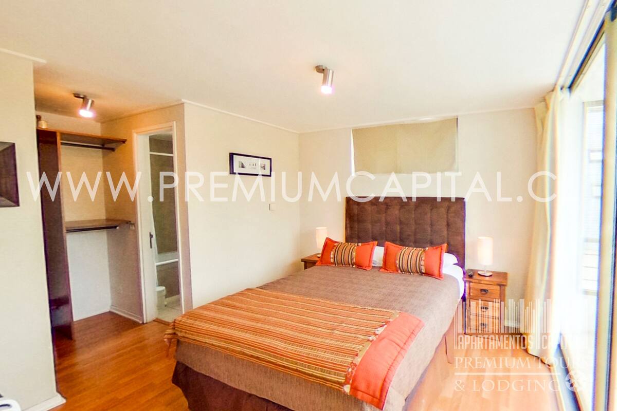 A bedroom with a bed, bedside table, and a window.