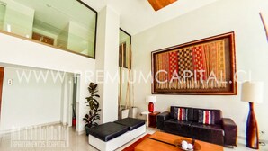 A modern living room with a sofa, coffee table, and a large abstract painting on the wall. - Apartamentos Premium Capital Casino Viña Del Mar (Vina del Mar)