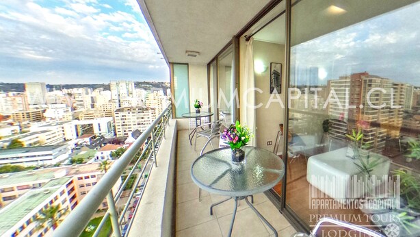 A balcony with a glass table and chairs, a potted plant, and a city view. - Apartamentos Premium Capital Casino Viña Del Mar (Vina del Mar)