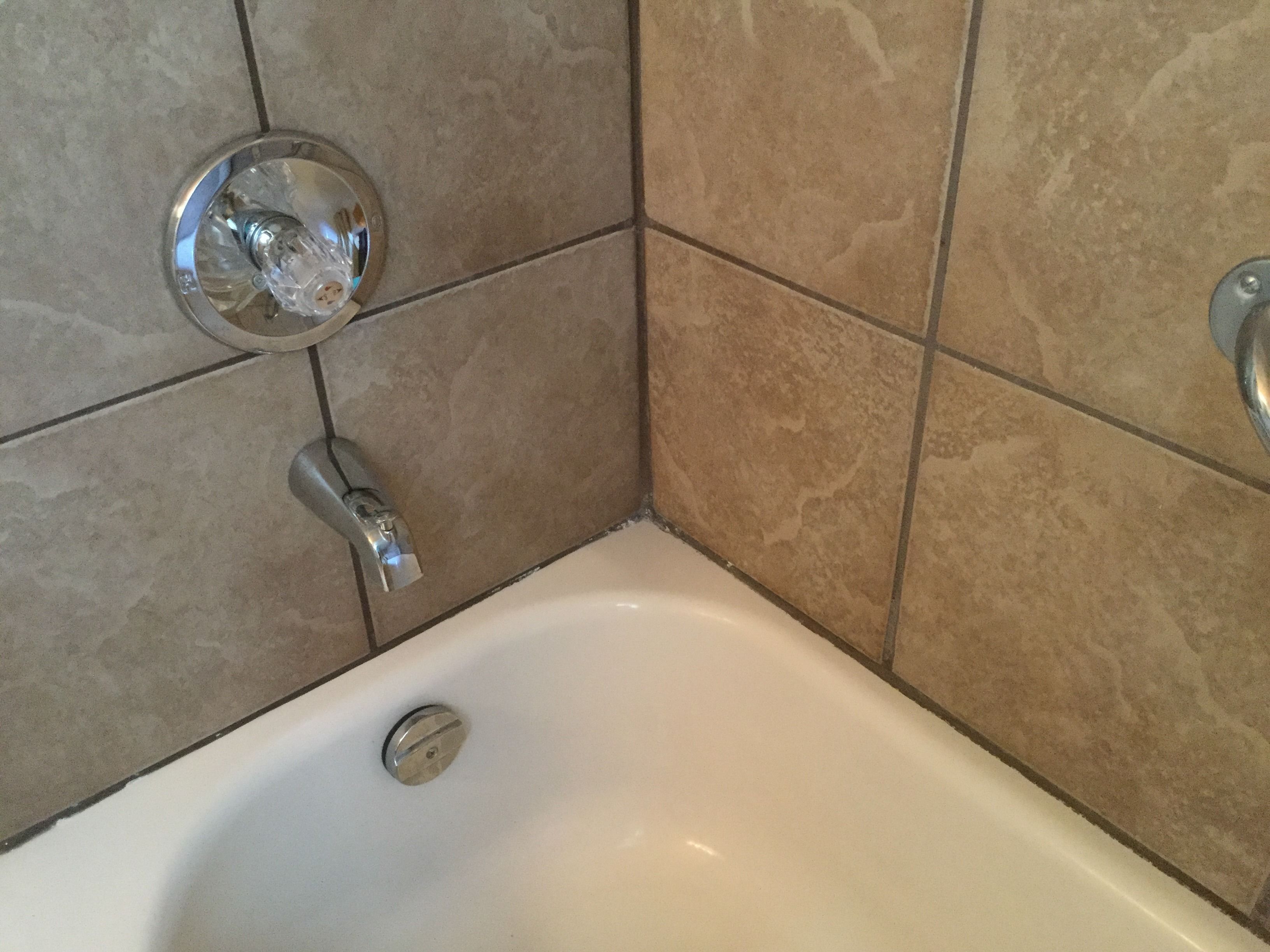 A bathroom with a white bathtub, a chrome faucet, and beige tiled walls.
