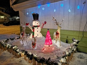 A snowman with a black top hat and scarf, a pink cone, and a reindeer with a red bow.