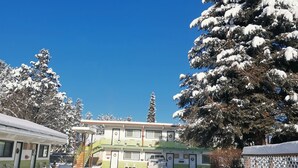 A snow-covered outdoor area with a building featuring multiple windows and a staircase. - Cedars Motel (Princeton)