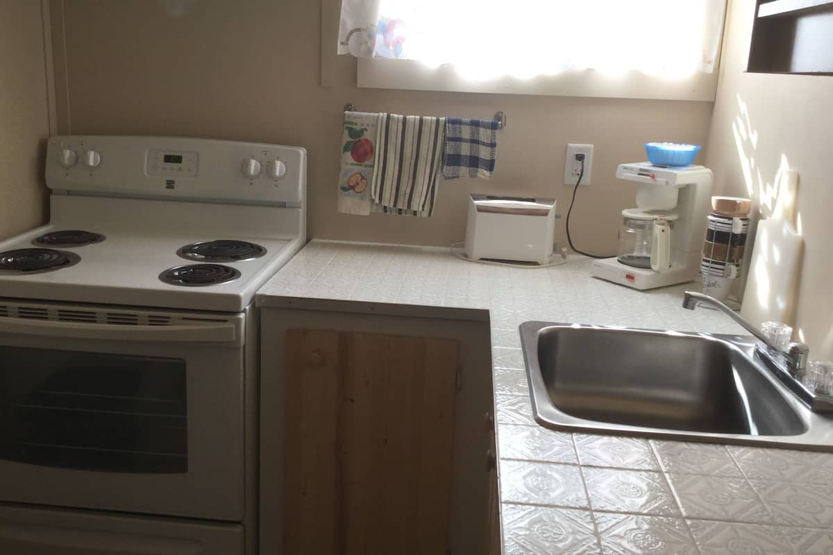 Una cocina con estufa, tostadora, cafetera y lavabo.
