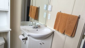 A bathroom with a white sink, mirror, and two towels hanging on the wall.