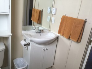 A bathroom with a white sink, mirror, and two towels hanging on the wall.