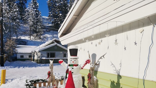 A snowman decoration with a red hat and scarf, a reindeer, and a snow-covered fence. - Cedars Motel (Princeton)