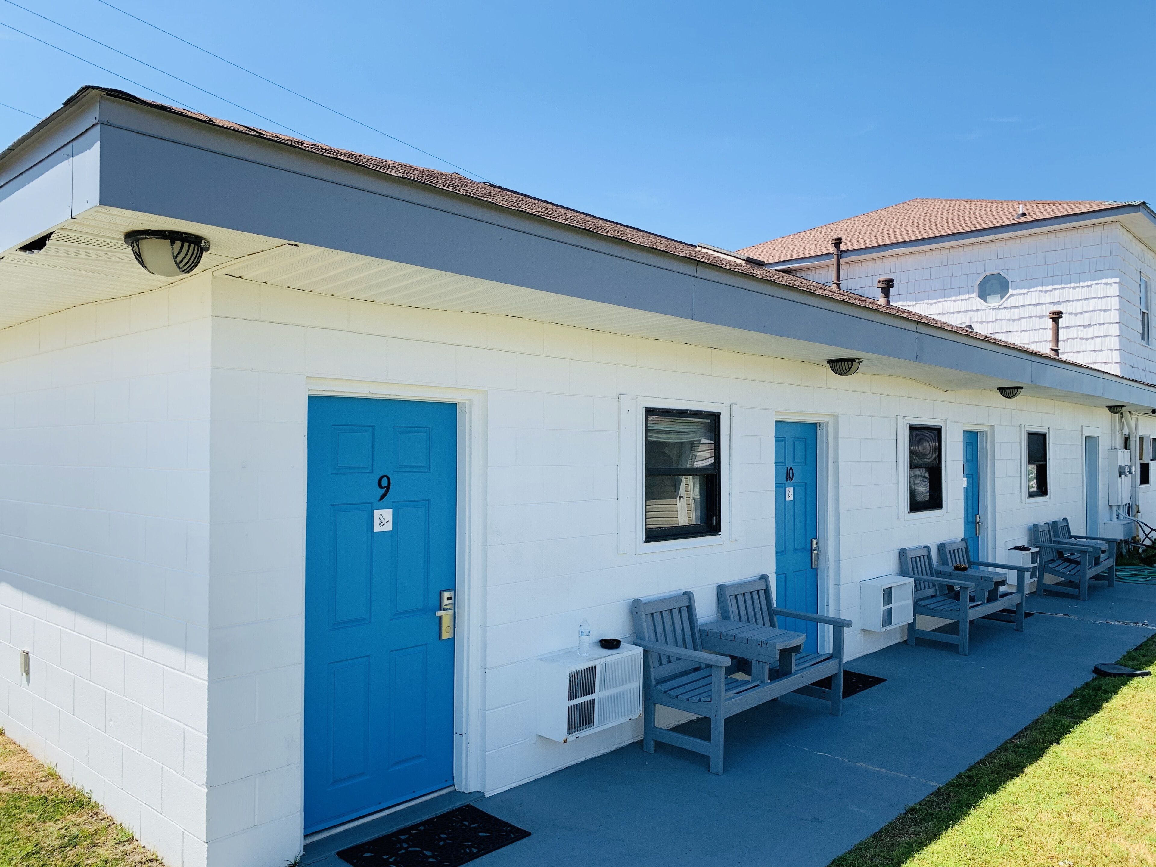A white building with blue doors, numbered 9 and 10, and a porch with benches.