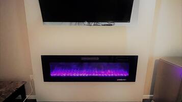 A flat-screen TV mounted above a built-in fireplace with a purple-lit fire.