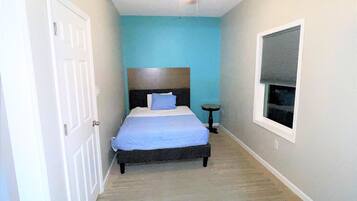 Quarto com cama, ventilador de teto, janela e porta.