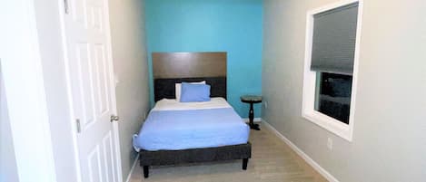 Un dormitorio con cama, ventilador de techo, ventana y puerta.