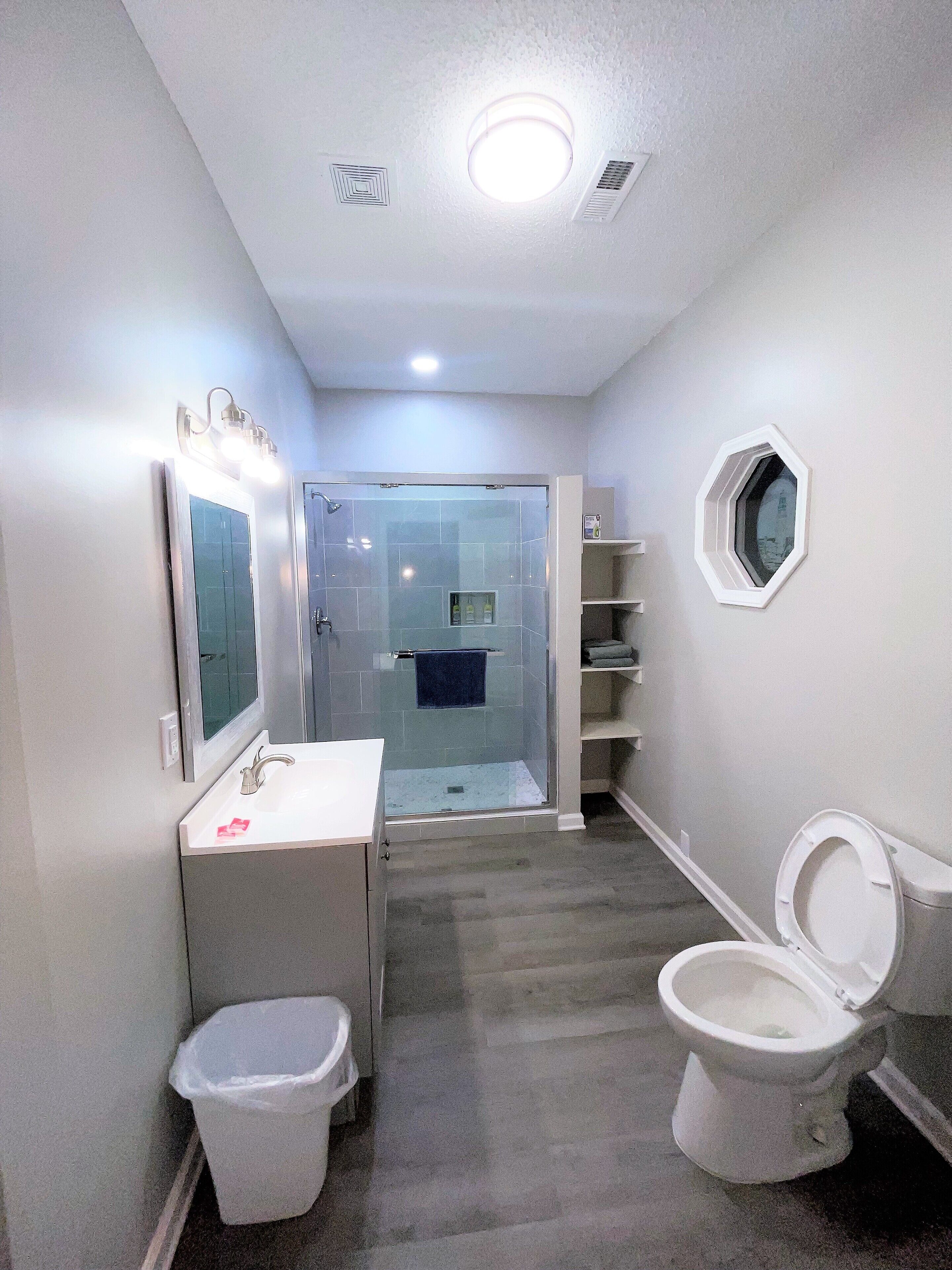 Baño con ducha, inodoro, lavabo y espejo.