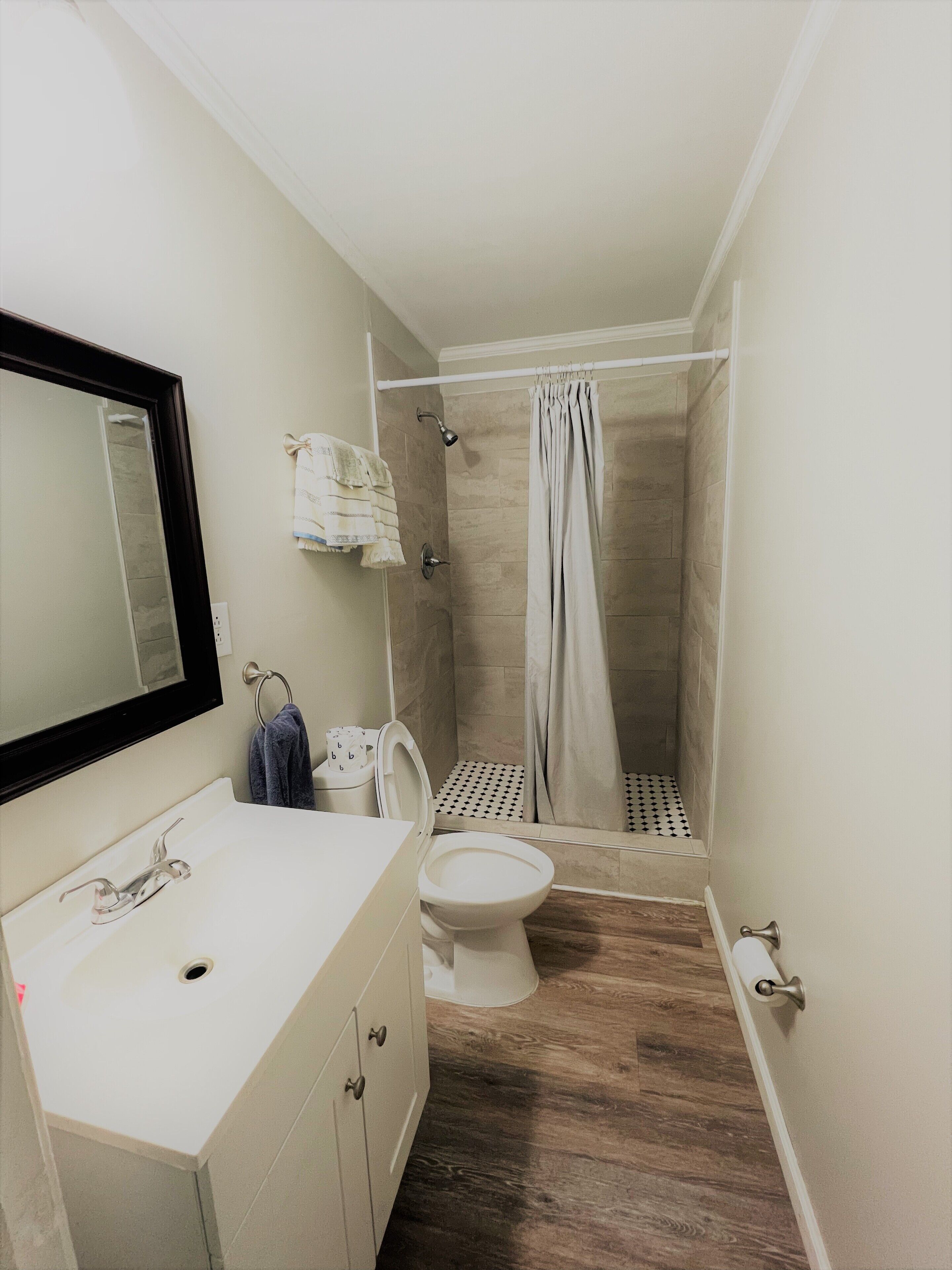 Un baño con lavamanos, inodoro y zona de ducha blancos.