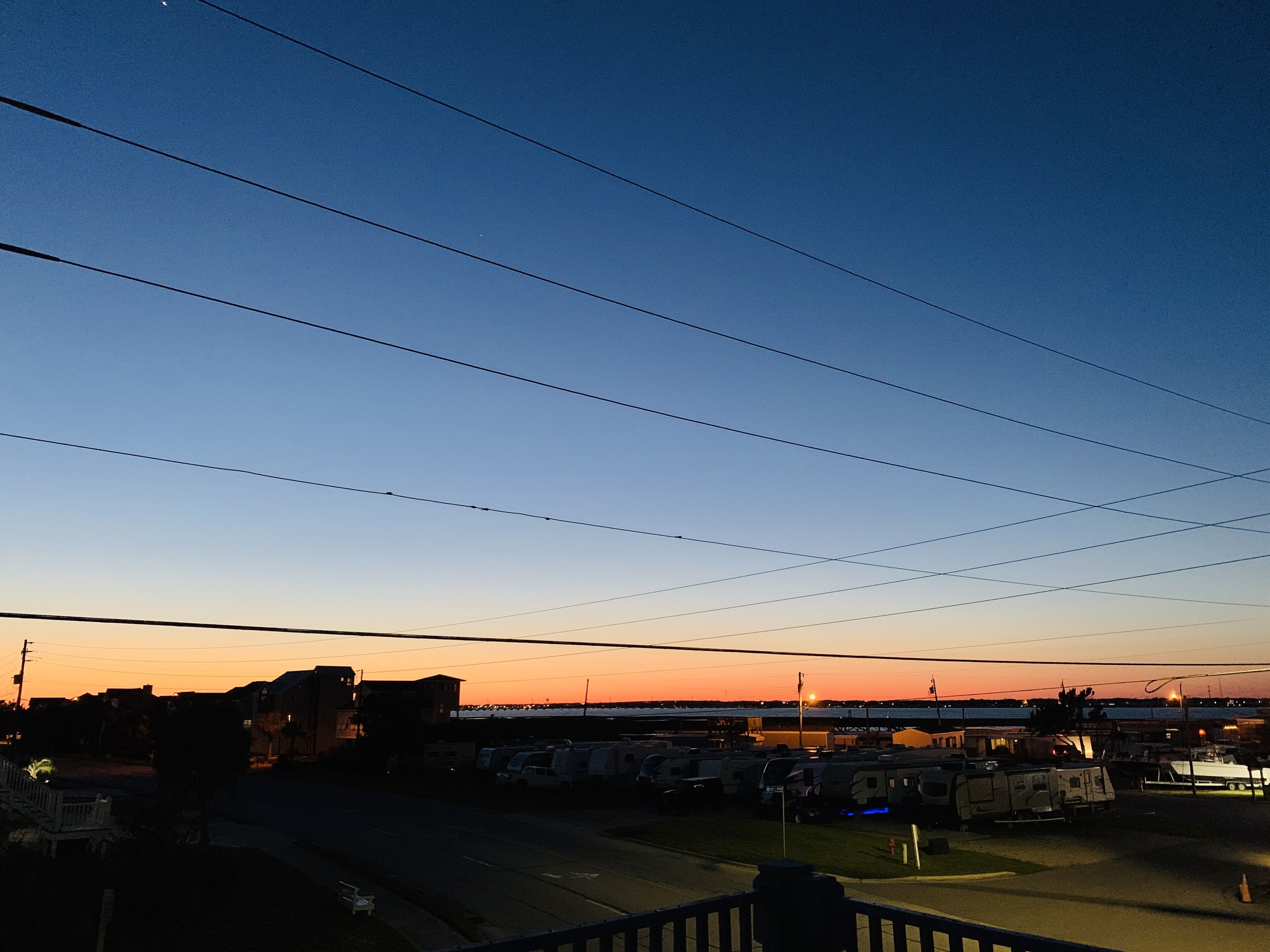 A parking lot with multiple vehicles, including RVs and trailers, under a clear sky.