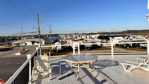 A view from a balcony overlooking a marina with boats, a clear sky, and a distant cityscape. - Sand Dollar Motel (Atlantic Beach)