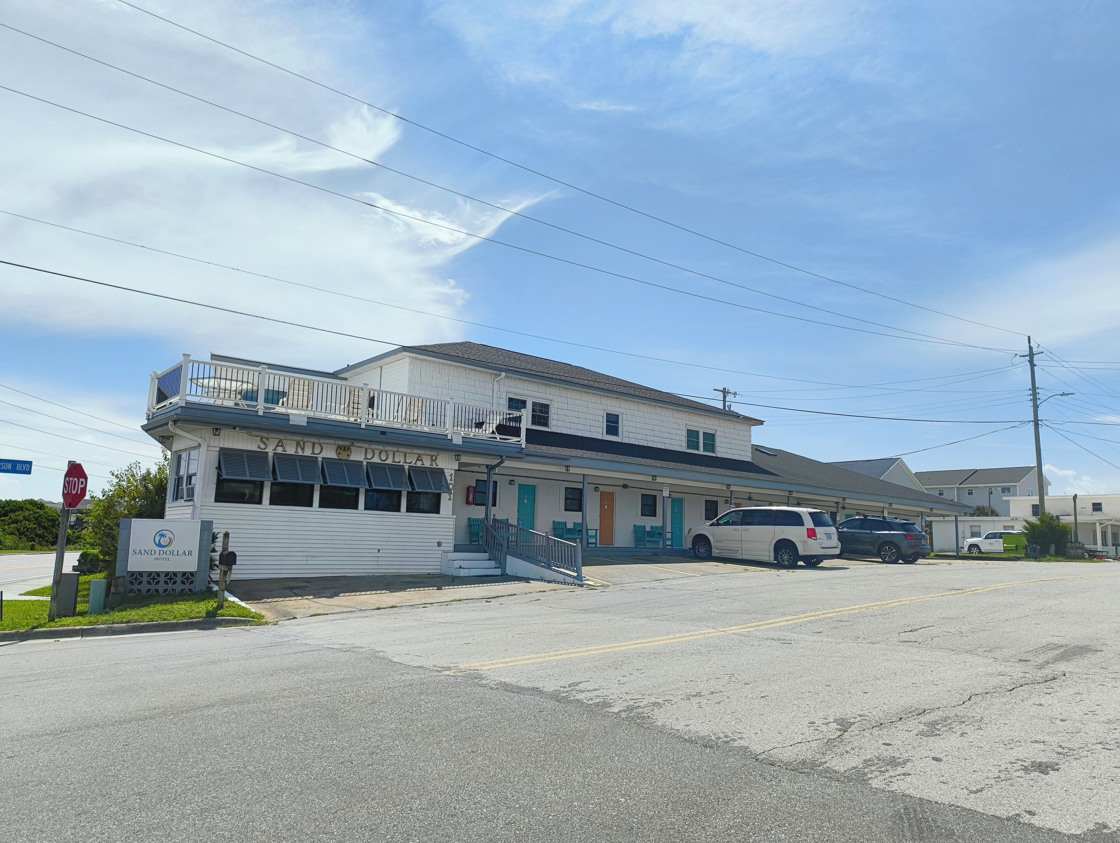 Un motel con balcón, una señal de stop y cielo despejado.