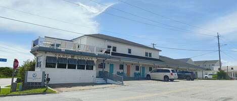 Un motel con balcón, una señal de stop y cielo despejado.
