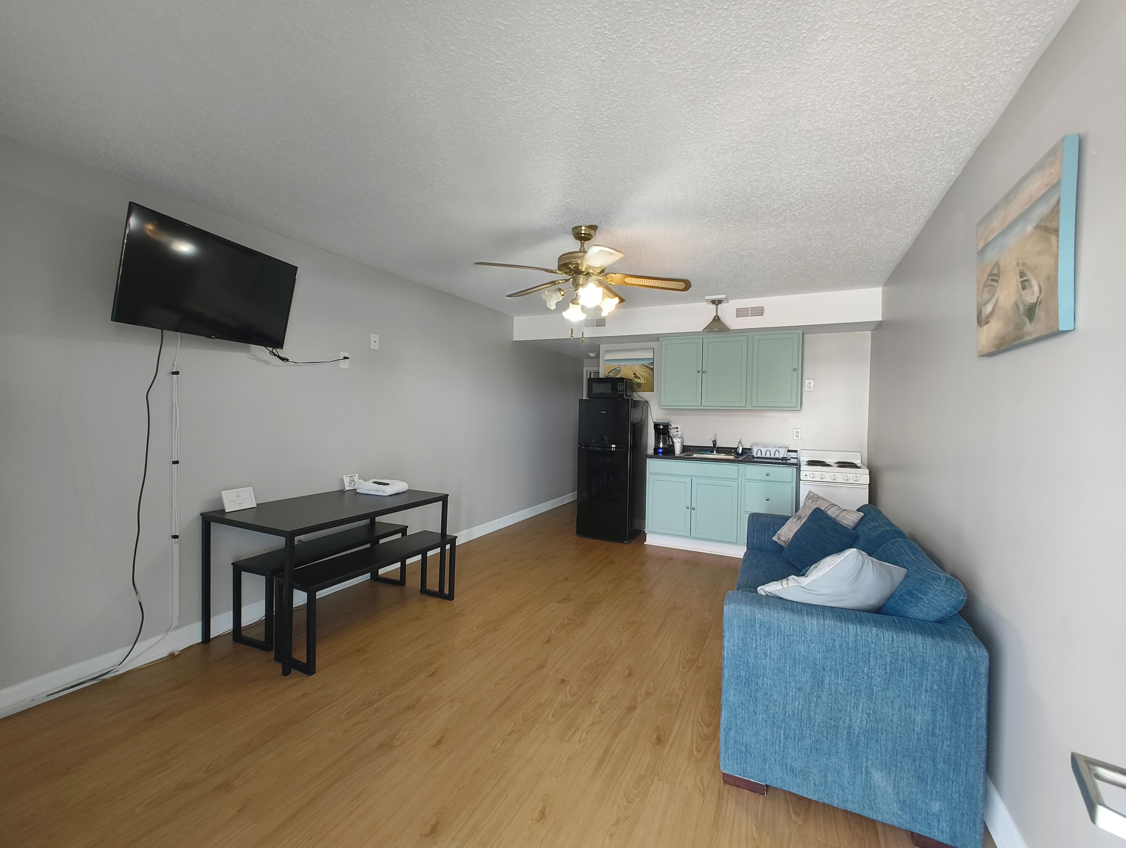 Un espace de vie compact comprenant un coin repas, une kitchenette et un ventilateur de plafond.
