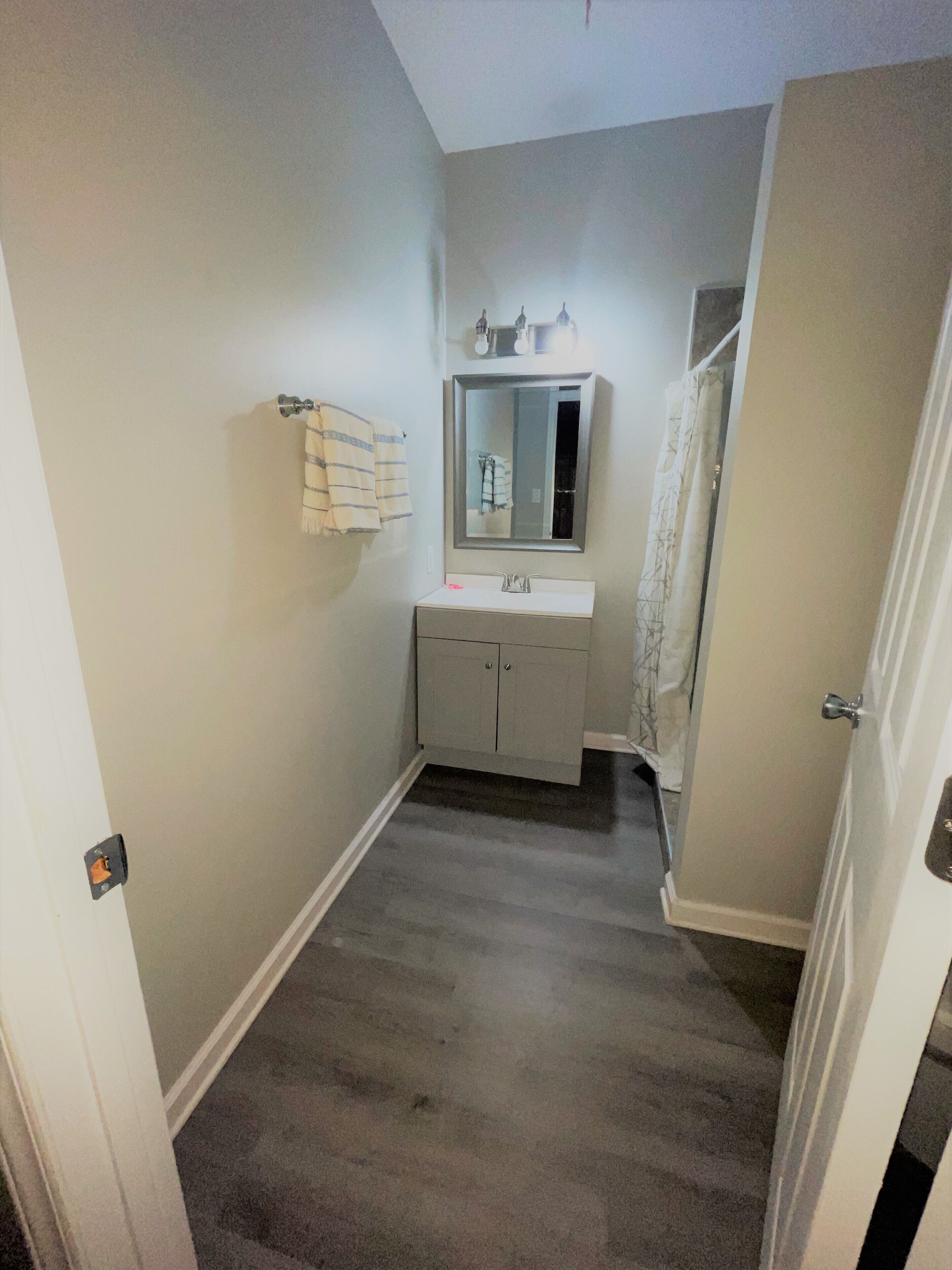 Une petite salle de bain avec un lavabo blanc, un miroir et un porte-serviettes.