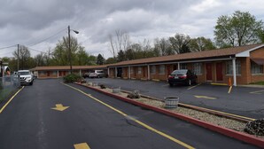 A motel with multiple rooms, a parking lot, and a red curb. - Economy Inn (Taylorville)