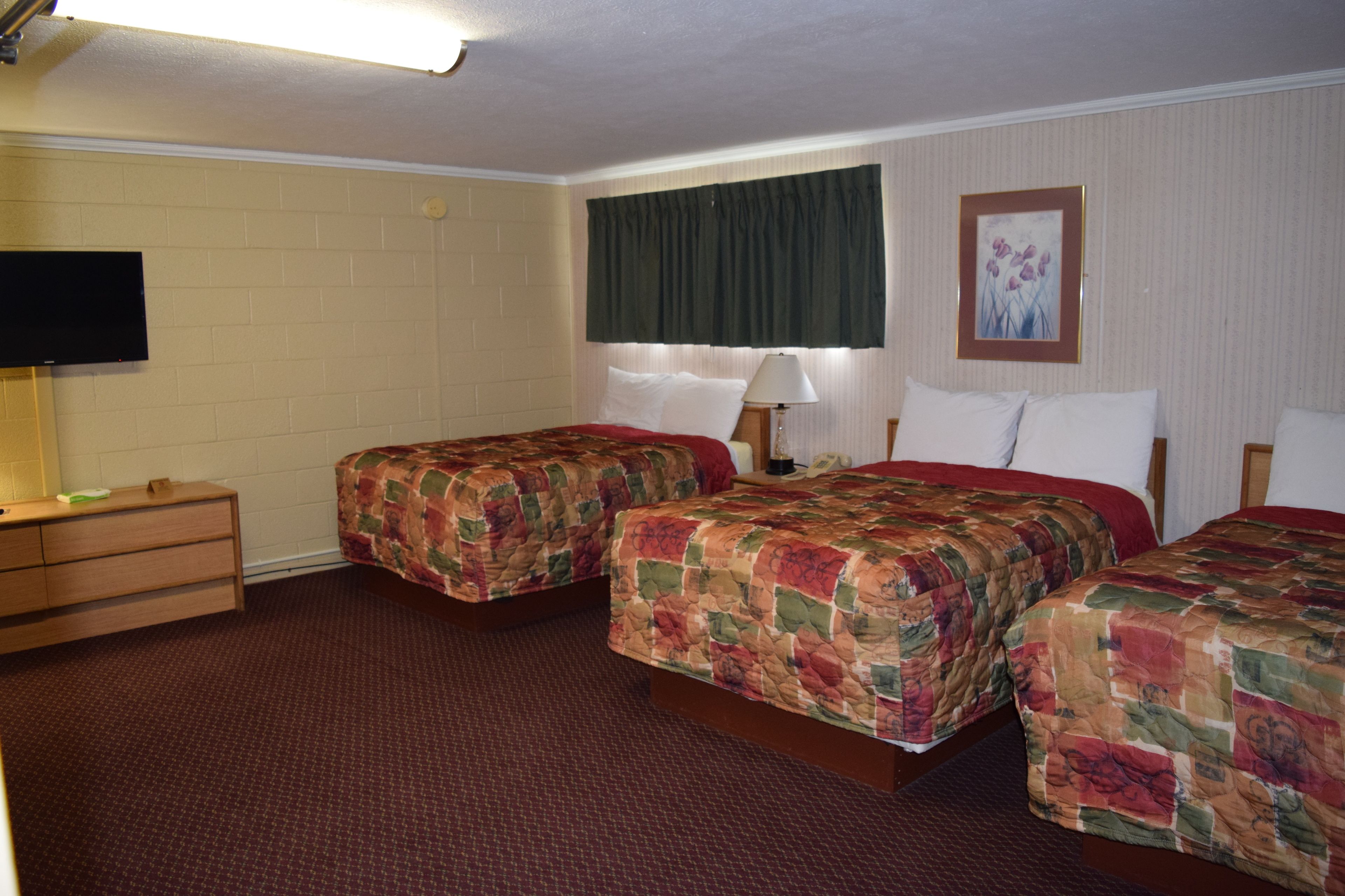 Habitación de hotel con dos camas, un televisor, un aparador y un cuadro en la pared.