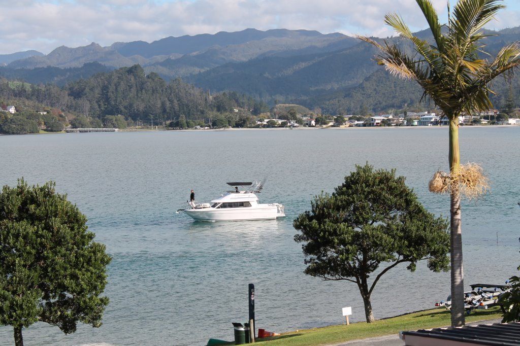 A lake with a boat, trees, and mountains in the background.