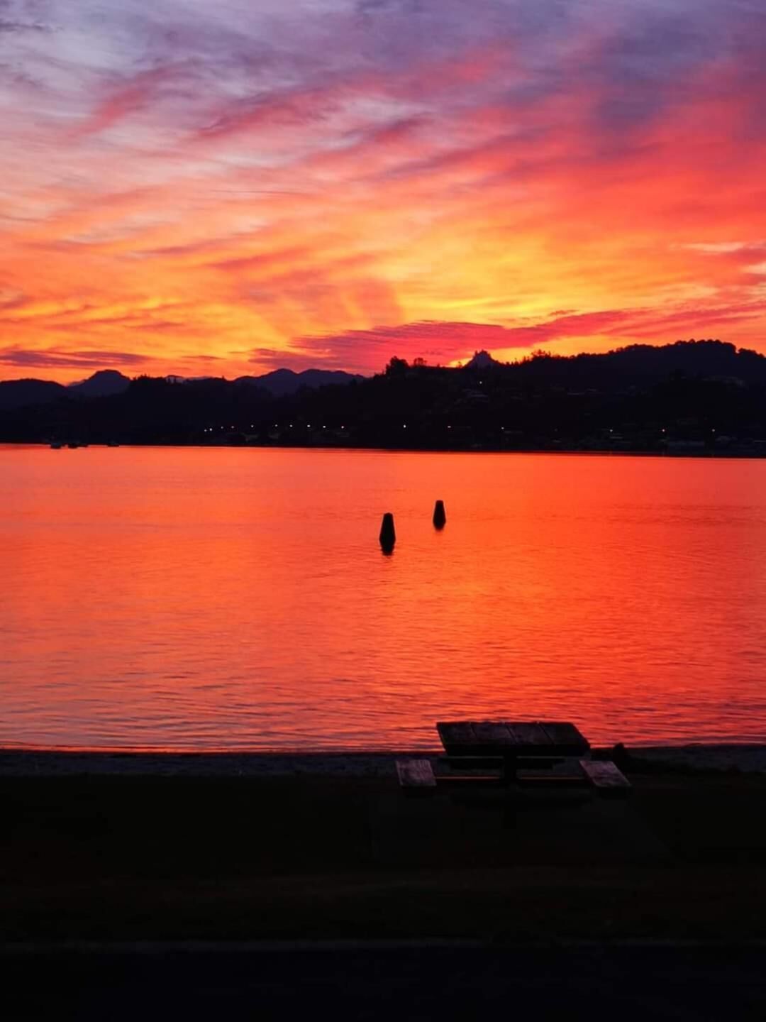 A sunset over a calm lake with a dock in the foreground.
