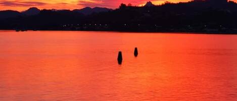 Ein Sonnenuntergang über einem stillen See mit einem Steg im Vordergrund.