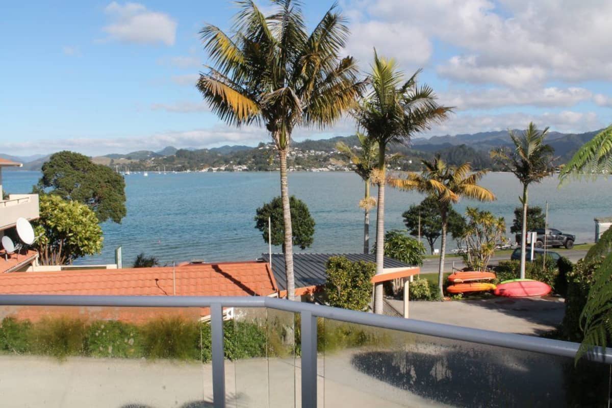 A coastal view with a clear sky, palm trees, and a body of water.