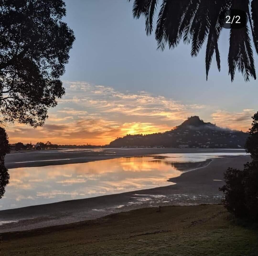 Una vista del atardecer sobre aguas tranquilas con una colina al fondo.