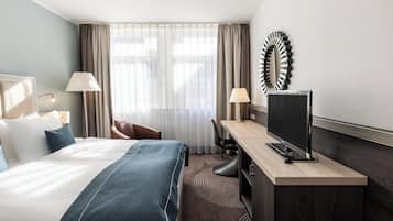 A hotel room with a bed, a desk, a TV, and a chair.