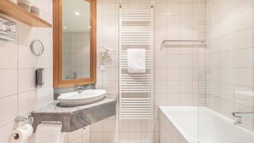 A bathroom with a marble sink, a mirror, a towel rack, and a shower area.