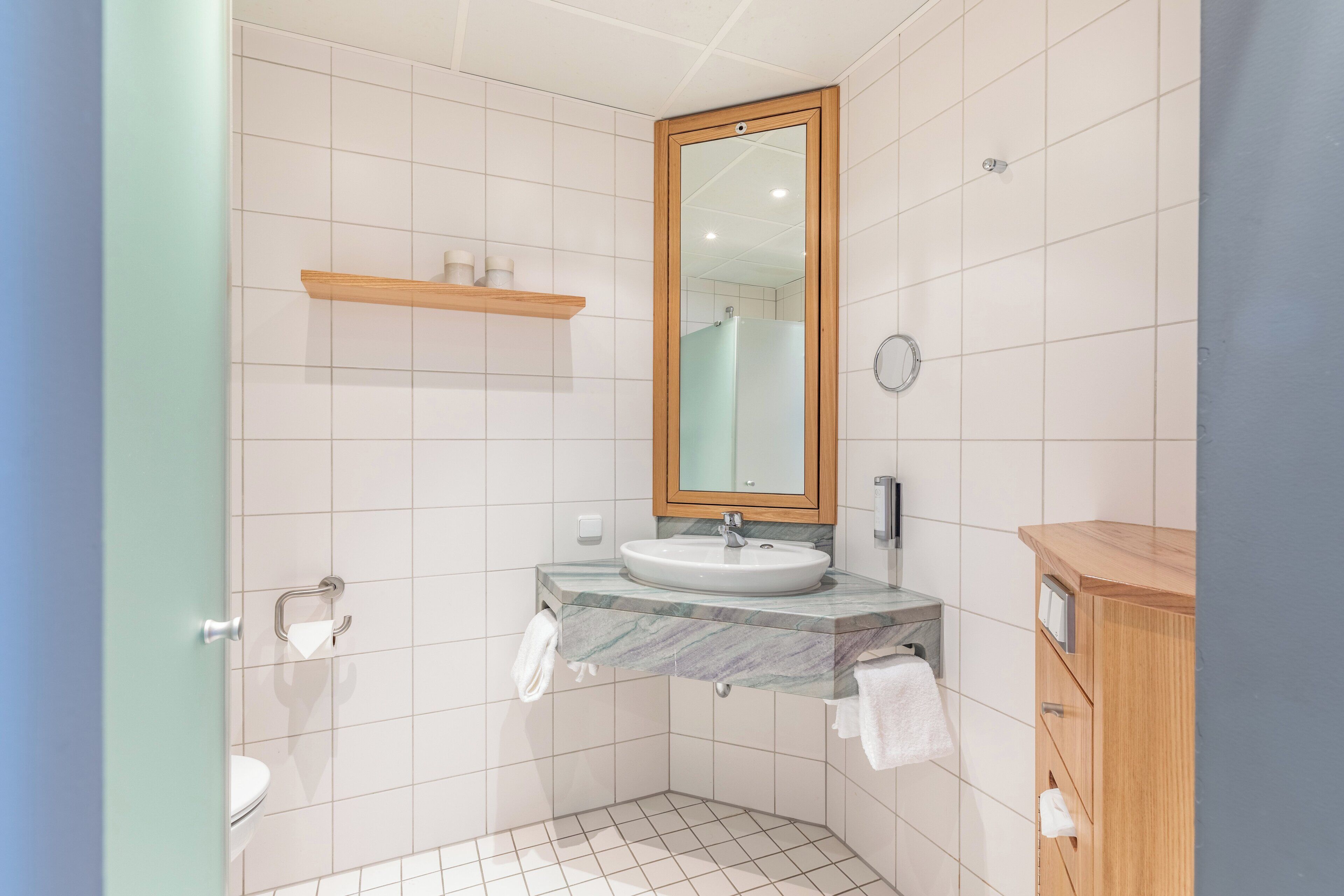 A bathroom with a white sink, mirror, and wooden vanity.