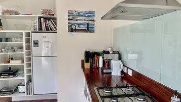 A kitchen with a white refrigerator, a gas stove, and a coffee machine. There are books and kitchen utensils on the counter.