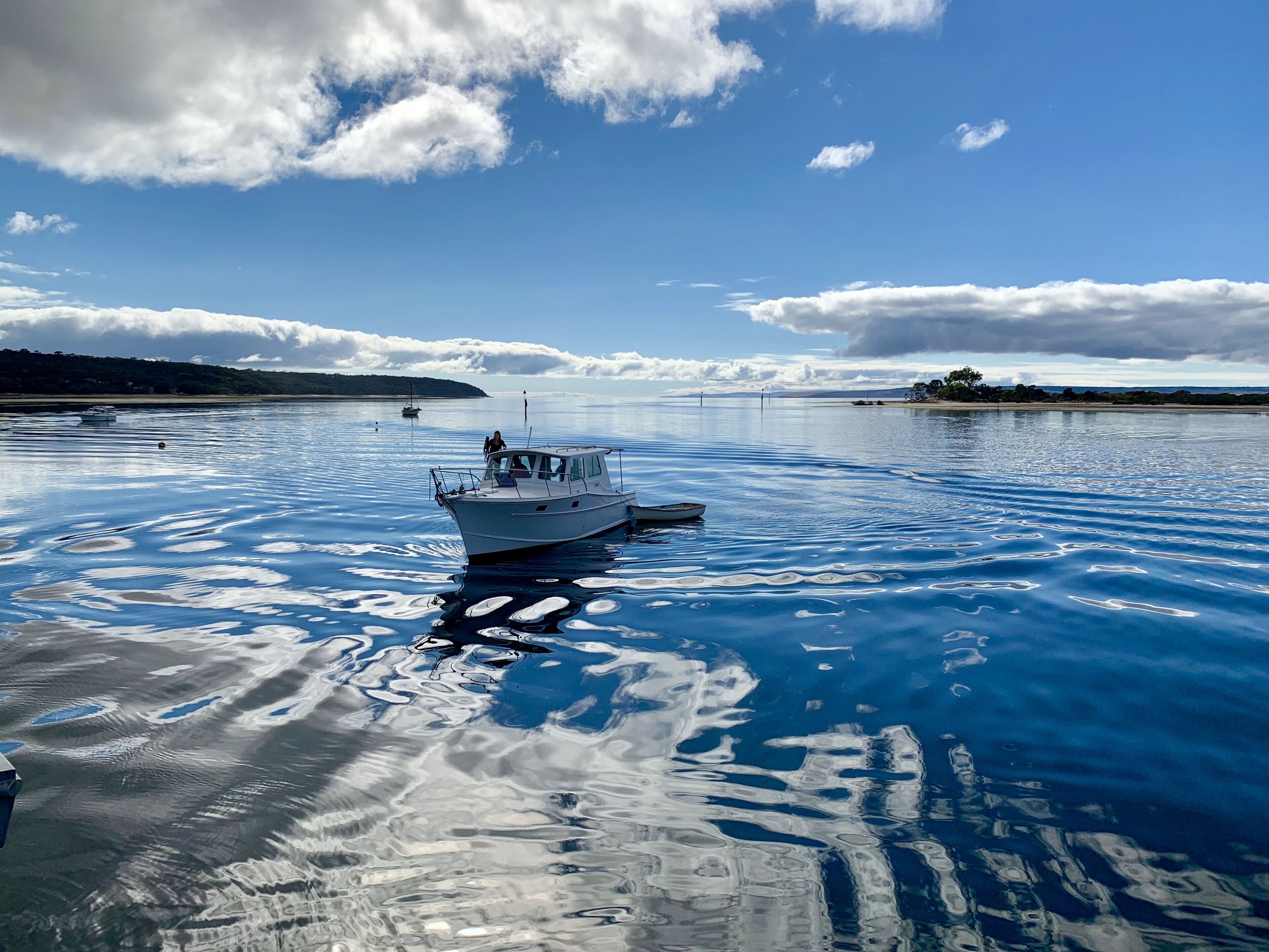 A boat on calm water with a clear sky and distant land.