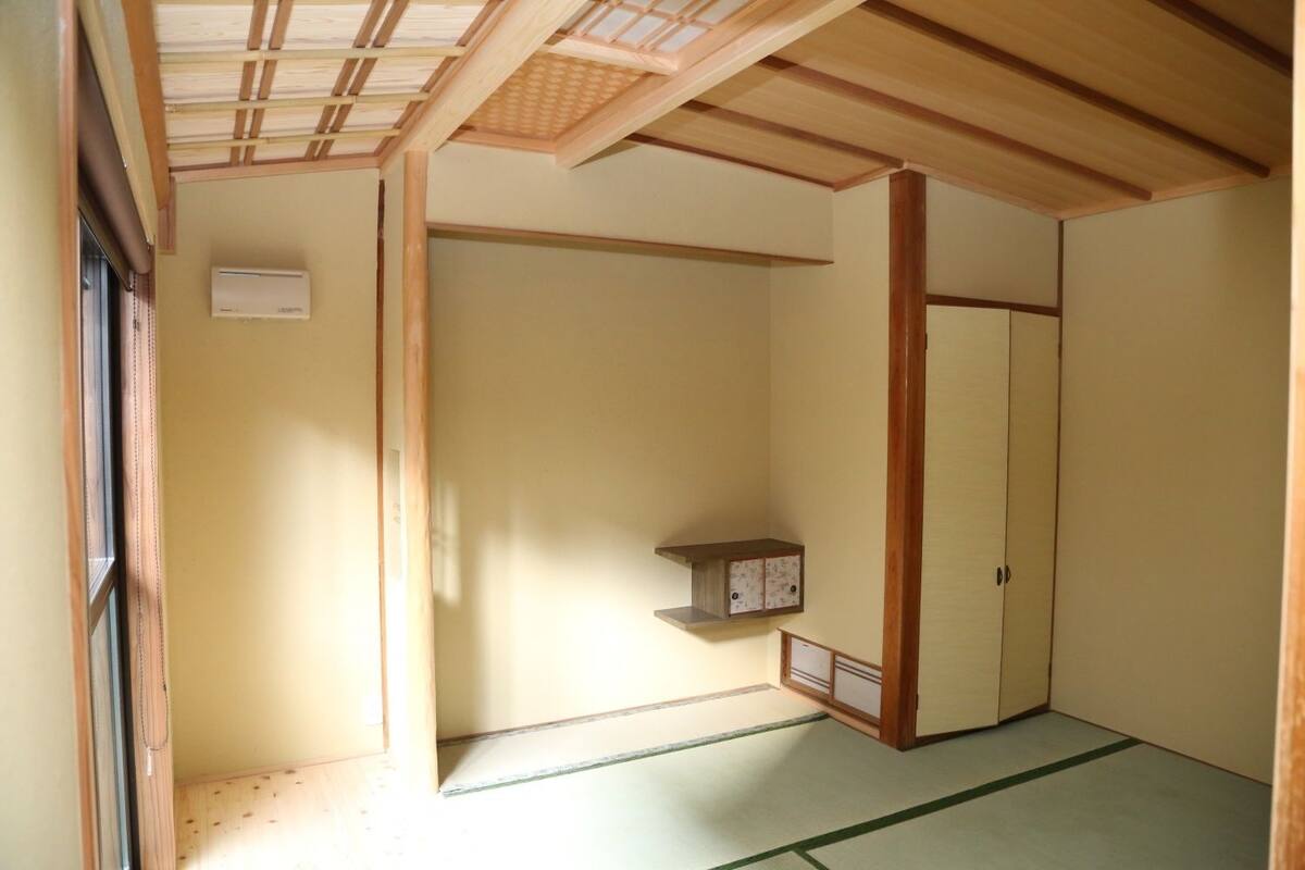 Een traditionele Japanse kamer met tatami vloeren, een schuifdeur, een klein plankje en een kledingkast.