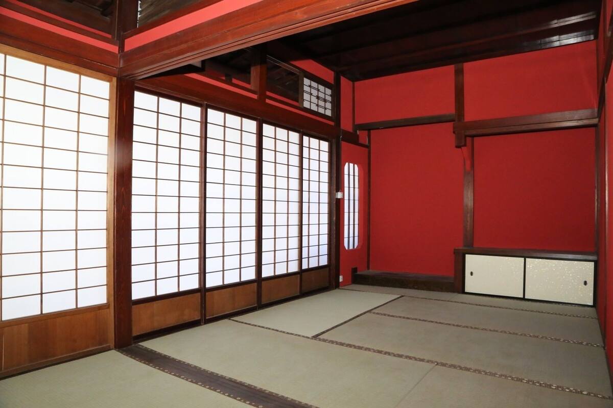 Een traditionele Japanse kamer met tatami vloeren, schuifdeuren en een rode wand.
