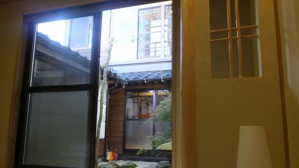 Een traditionele Japanse kamer met tatami vloerbedekking, een schuifdeur en uitzicht op een tuin met rotsen en planten.