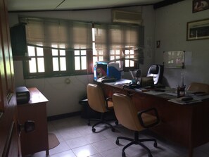 A small office with a desk, two chairs, a computer, and a window with blinds.