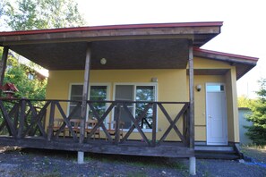 A yellow building with a wooden porch and a red roof. - Tocotoco House (Nakafurano)