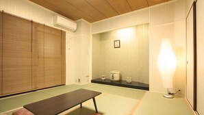 Ett traditionellt japanskt rum med tatamimattor på golvet, ett lågt bord, en futon och en shojiskärm.