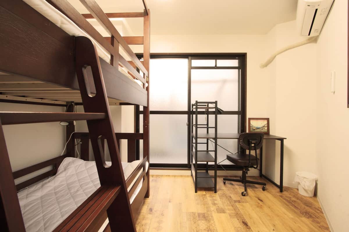 A compact room with a bunk bed, a desk with a chair, and a window with a view.