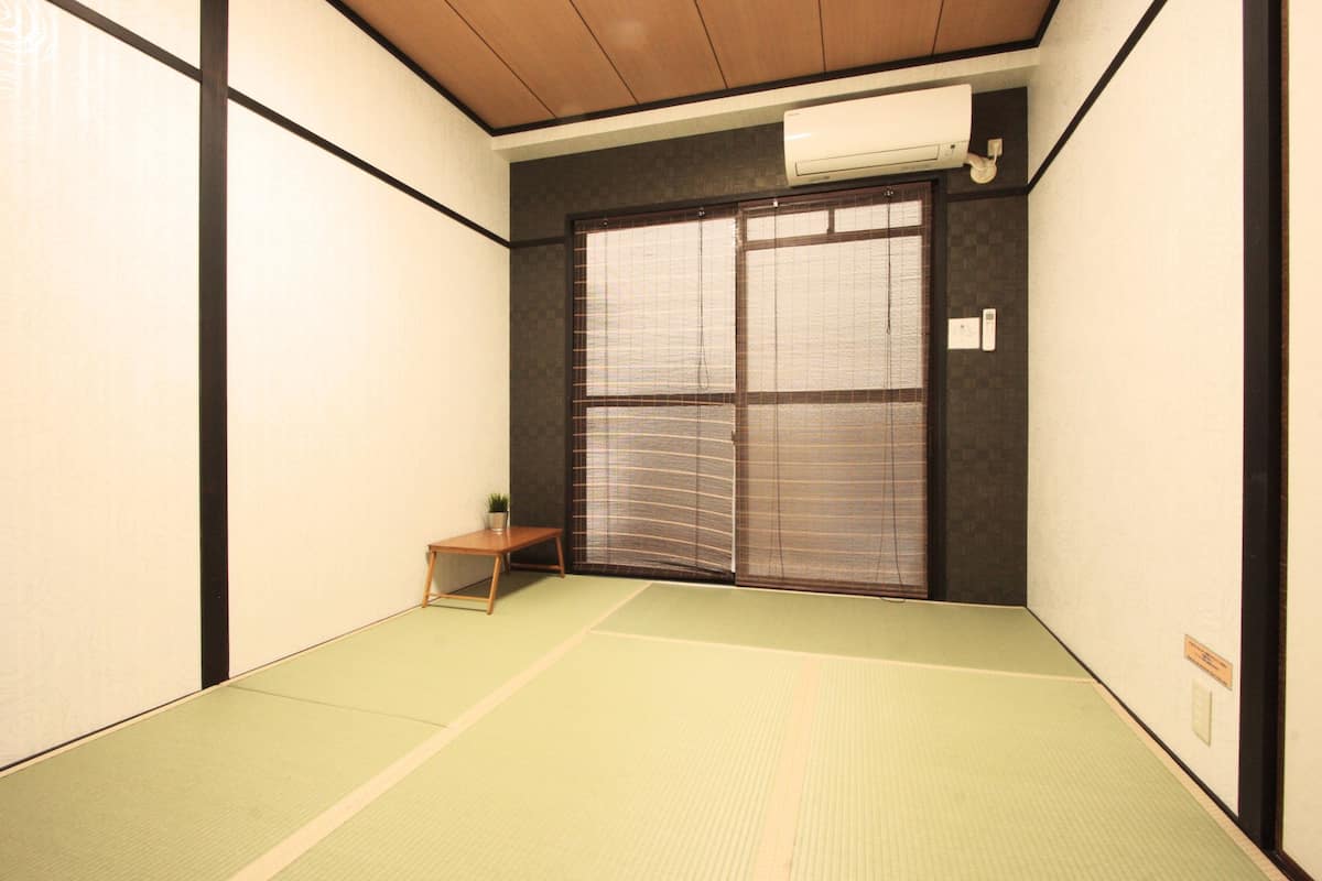 A traditional Japanese room with tatami flooring, a sliding door, and a small table with a plant.