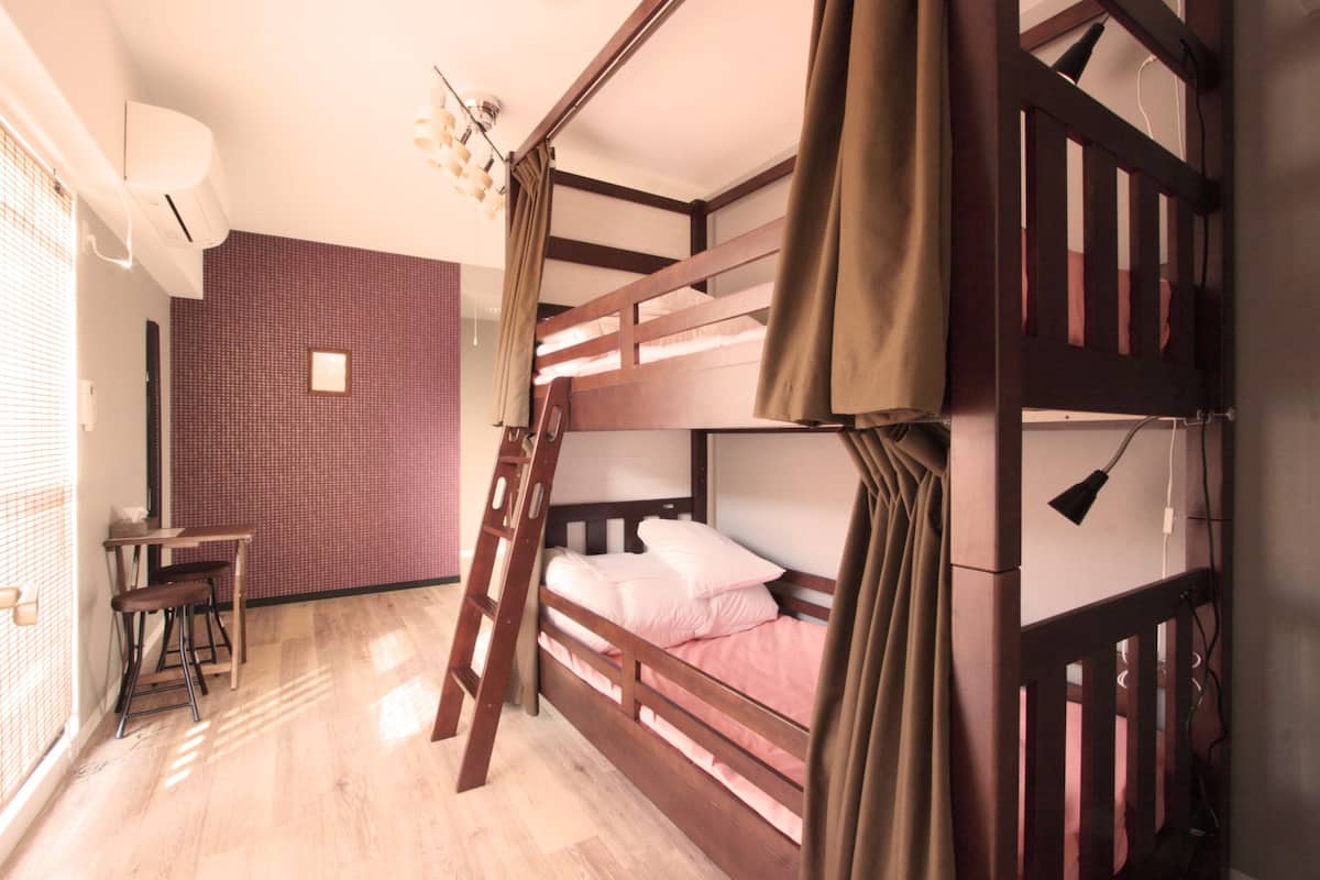 A bunk bed room with a desk and chair, a ladder, and a patterned wall.