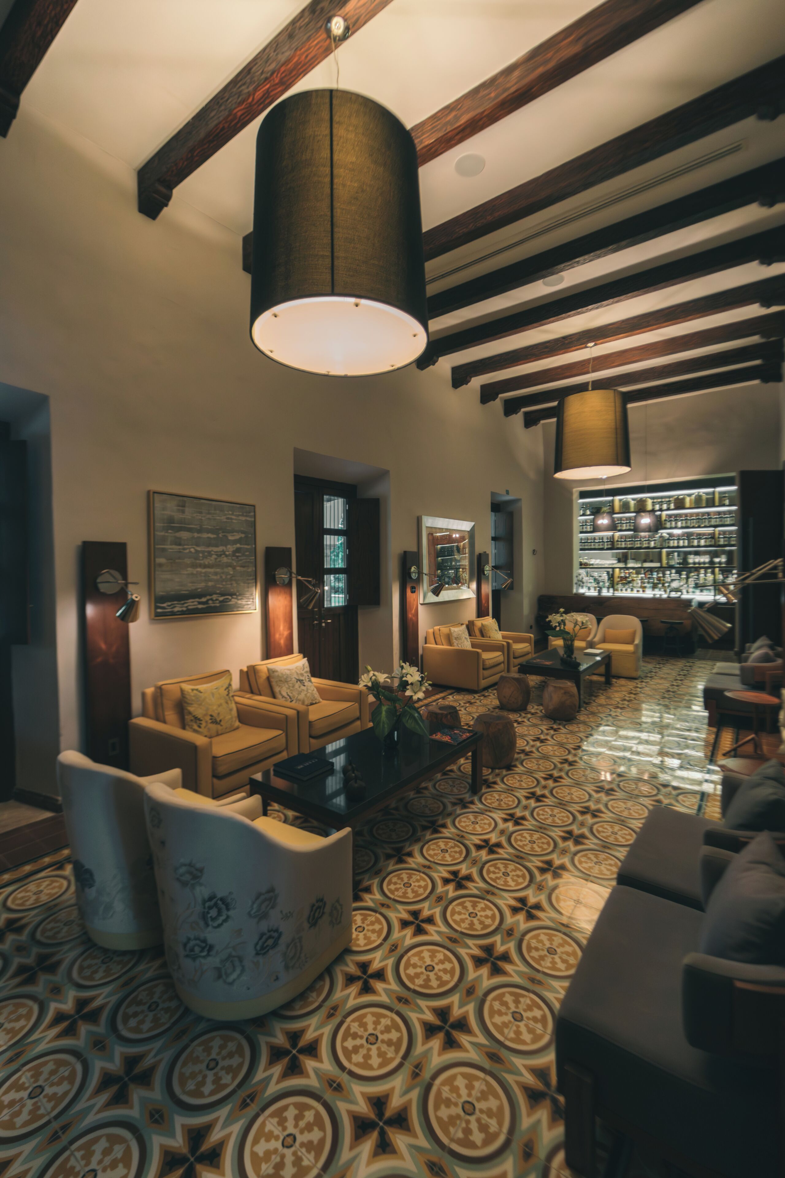 Un amplio salón con suelo estampado, sofás y un bar al fondo.