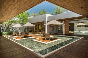Terrassa exterior moderna amb una piscina rectangular, paviment de fusta i mobiliari d'exterior amb ombrel·les.