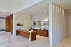 A modern reception area with a wooden reception desk, a stone wall, and framed artwork on the wall.