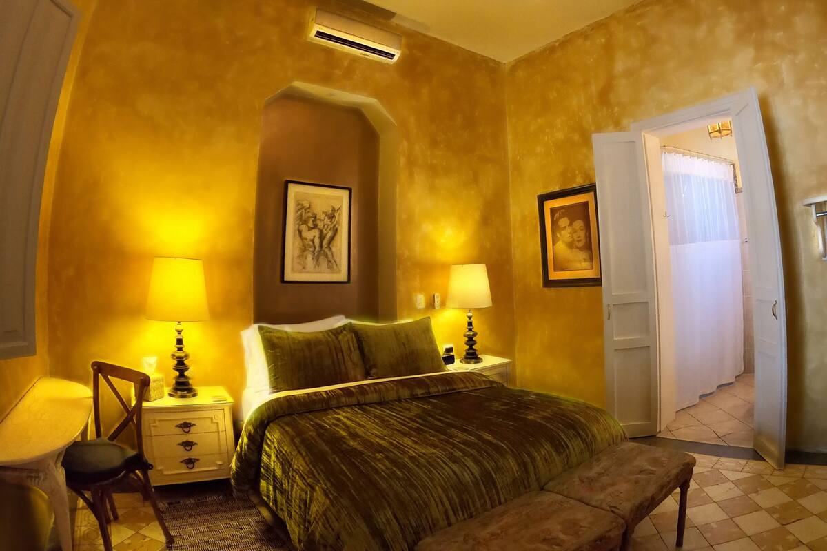 A bedroom with a bed, two bedside tables with lamps, a chair, and a bench.