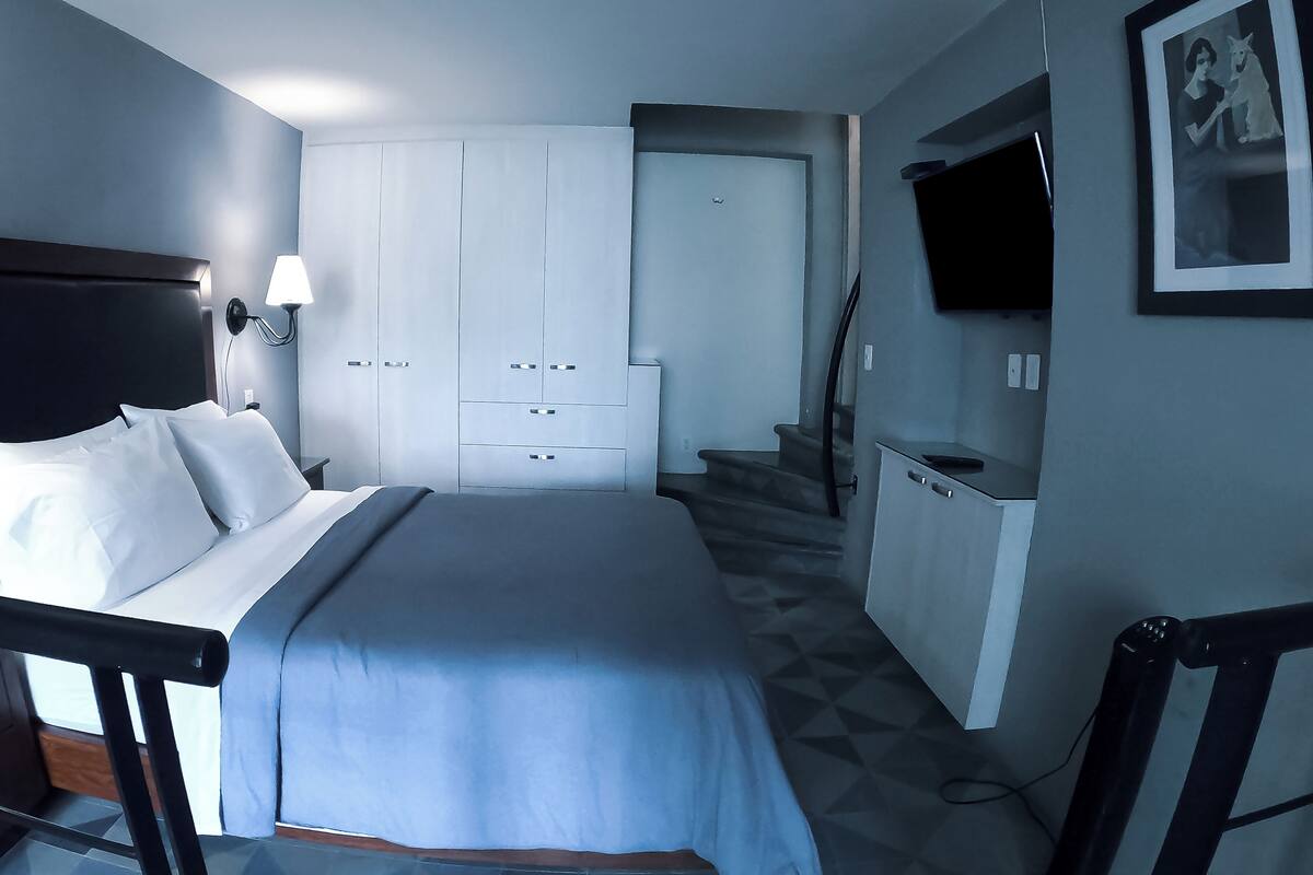 A hotel room with a bed, a desk, a wardrobe, and a TV on the wall.